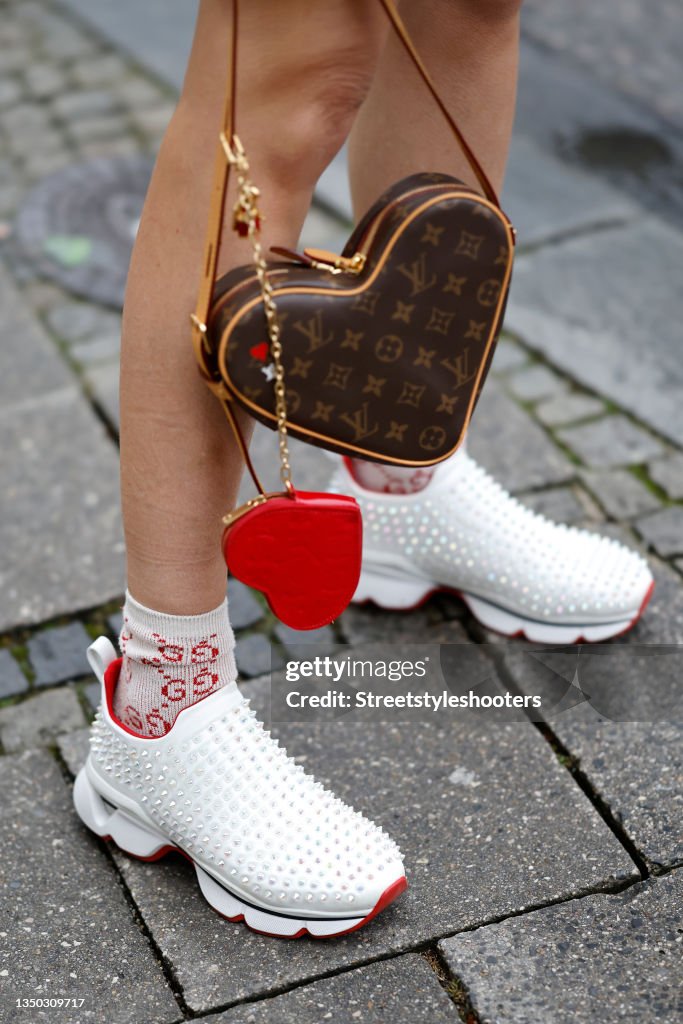 A brown and red heart bag by Louis Vuitton, white studded sneakers
