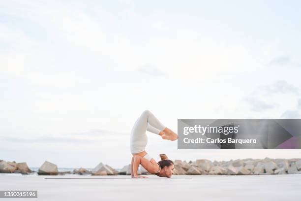 side view of a flexible lady lifting both legs and putting her feet close to her head - al revés posición descriptiva fotografías e imágenes de stock