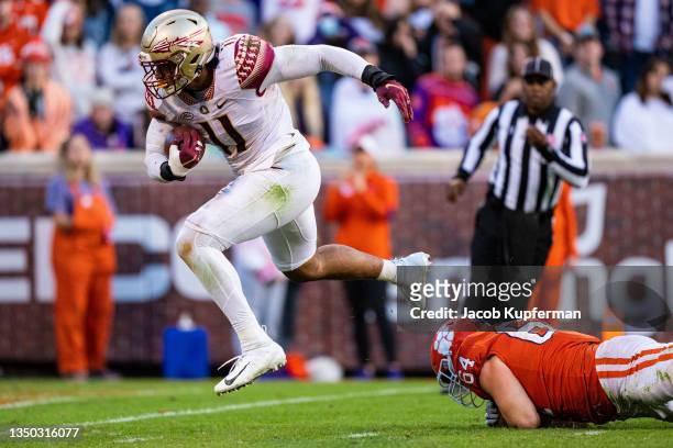 Defensive end Jermaine Johnson II of the Florida State Seminoles scores a defensive touchdown while eluding offensive lineman Walker Parks of the...
