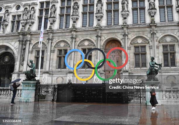 People take pictures with the sign of the Olympic rings in the rain in front of the City Hall of Paris to mark the 1,000-day countdown to the Paris...