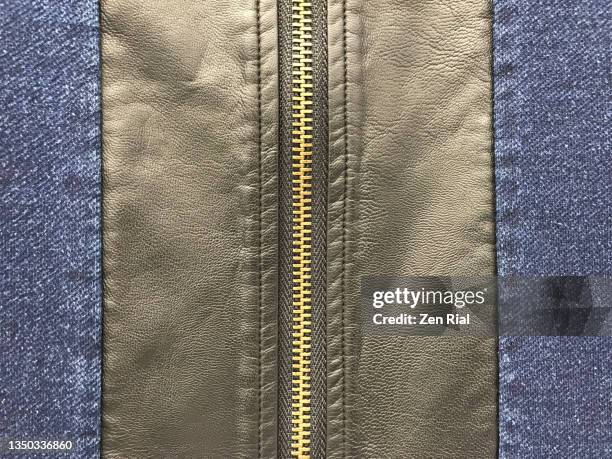 gold colored zipper on a synthetic leather and denim fabric, backside of dress - double denim stock-fotos und bilder