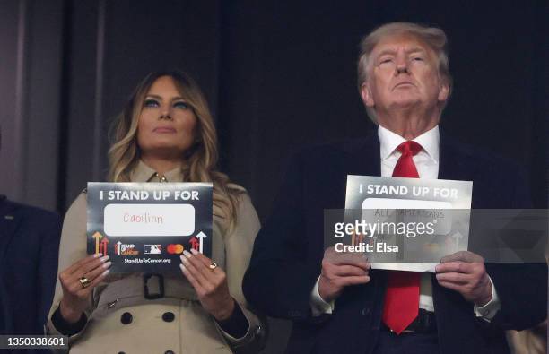 Former first lady and president of the United States Melania and Donald Trump hold up signs for "stand up to cancer" prior to the sixth inning in...