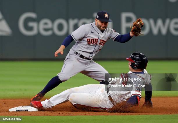 Austin Riley of the Atlanta Braves slides in safely under the tag of Jose Altuve of the Houston Astros at second base after advancing on the throw...