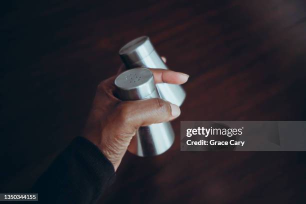 woman grabs salt and pepper shakers from kitchen table - pepper pot stock pictures, royalty-free photos & images