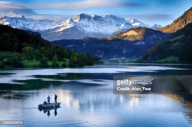 fishing on lake lungern - swiss village lungern in switzerland - snow boot stockfoto's en -beelden