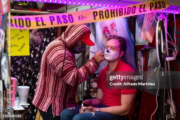 Tourist is having makeup done as a skull in a costume station at the Coyoacan market ahead of Day of the Dead on October 30, 2021 in Mexico City,...