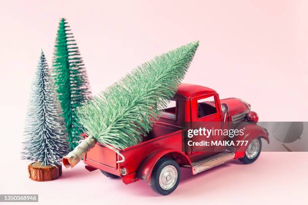 vintage red pick-up truck with toy christmas tree on pink background. christmas and new year concept. - christmas truck stock pictures, royalty-free photos & images