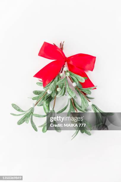 directly above of christmas mistletoe branch with bow of red ribbon on white background. christmas and new year concept. - mistletoe kiss stockfoto's en -beelden