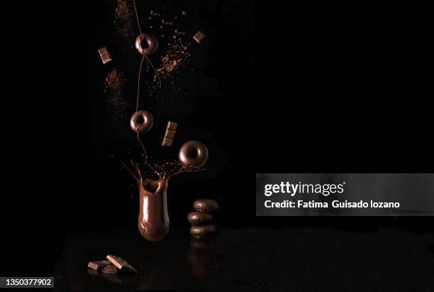 glass of liquid dark chocolate, with doughnuts and flying chocolate chips - hundreds and thousands stock pictures, royalty-free photos & images