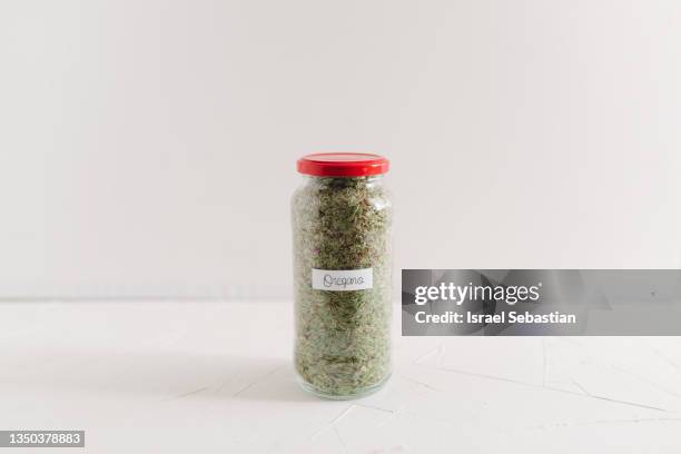 front view of a glass jar with dried oregano. - origano foto e immagini stock