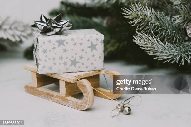 gift box with stars on wooden toy sled. - kegelvrucht stockfoto's en -beelden