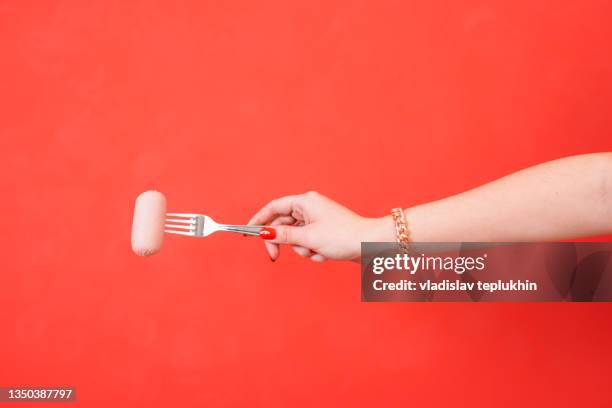 female hand holding a fork with sausage - フォーク ストックフォトと画像