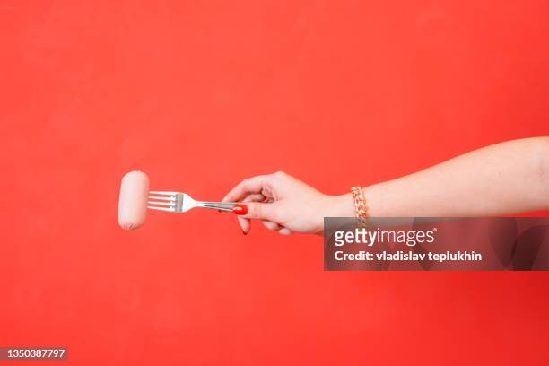 female hand holding a fork with sausage - meat fork stock pictures, royalty-free photos & images