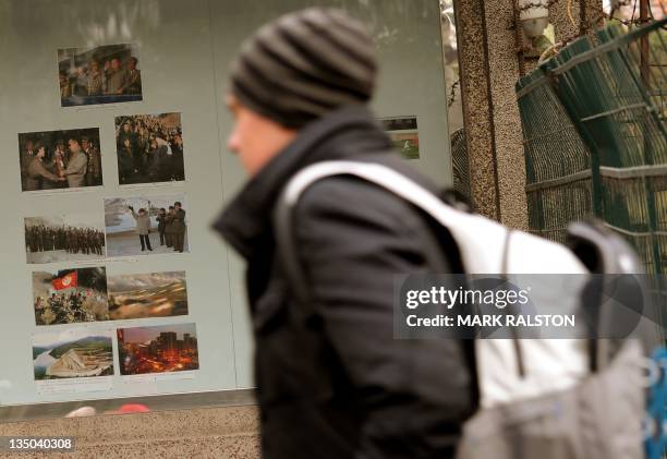 Westerner walks past propaganda posters showing the North Korean leader Kim Jong-Il outside the North Korean embassy in Beijing on December 6, 2011....