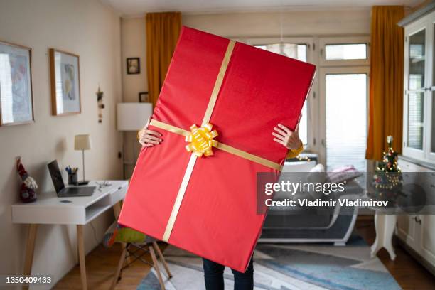 halten mit beiden händen ein sehr großes weihnachtsgeschenk - christmas presents stock-fotos und bilder