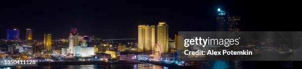 panoramic aerial view of the broadwalk on the waterfront in atlantic city downtown, the famous gambling center of the east coast usa, with multiple casinos and amusing park with a ferris wheel on a pier. - atlantic city stock pictures, royalty-free photos & images