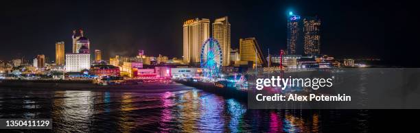 panoramic aerial view of the broadwalk on the waterfront in atlantic city downtown, the famous gambling center of the east coast usa, with multiple casinos and amusing park with a ferris wheel on a pier. - atlantic city imagens e fotografias de stock