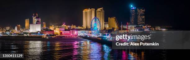 panoramic aerial view of the broadwalk on the waterfront in atlantic city downtown, the famous gambling center of the east coast usa, with multiple casinos and amusing park with a ferris wheel on a pier. - passeio de tábuas imagens e fotografias de stock