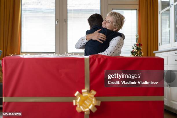 a small boy hugging his mum in thanks for the very large christmas present - big xmas stocking stock pictures, royalty-free photos & images