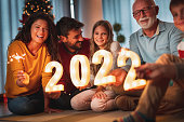 Family holding illuminative numbers 2022 while celebrating New Year