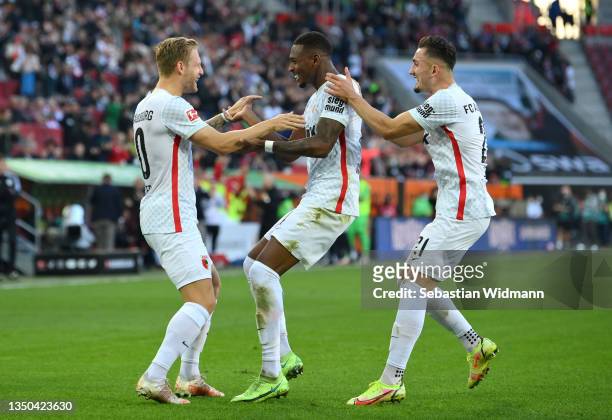Reece Oxford of FC Augsburg celebrates with teammates Arne Maier and Andi Zeqiri after scoring their side's first goal during the Bundesliga match...