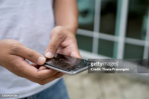 man holding a broken smart phone in his hand - cracked iphone stock pictures, royalty-free photos & images