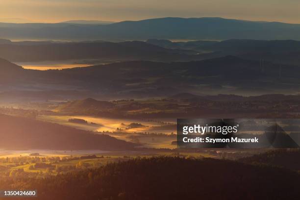 dunkle berglandschaft bei stimmungsvollem sonnenaufgangsdunst mit goldenem nebel im tal - riesengebirge stock-fotos und bilder