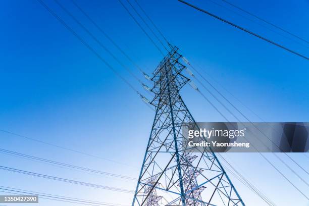 high voltage towers at blue sky background. power lines against the sky - alto voltaje fotografías e imágenes de stock
