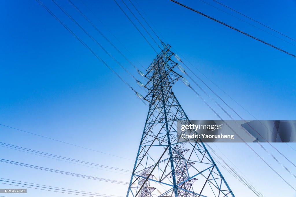 High voltage towers at blue sky background. Power lines against the sky