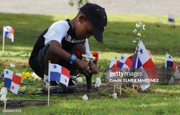 Boy puts flowers on the grave of a relative who died in the 1989 US invasion to Panama, at the Jardin de la Paz cemetery in Panama City on December...