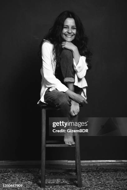 belle femme assise sur une chaise avec un sourire édenté, photo de studio, photo en noir et blanc - portrait of beautiful brunette woman smile photos et images de collection