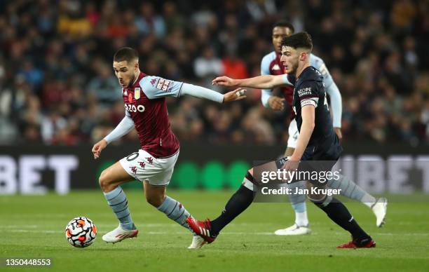 Emiliano Buendia of Aston Villa runs with the ball whilst under pressure from Declan Rice of West Ham United during the Premier League match between...