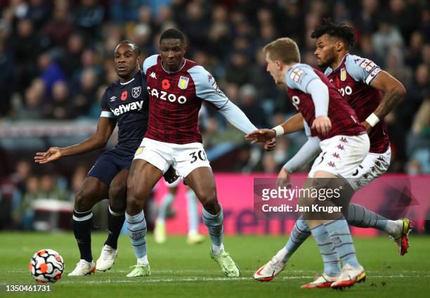 Michail Antonio of West Ham United passes the ball whilst under pressure from Kortney Hause of Aston Villa during the Premier League match between...
