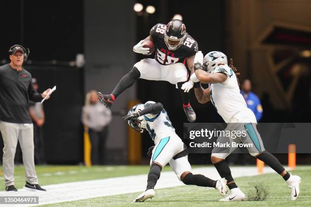 Mike Davis of the Atlanta Falcons runs with the ball while leaping over Sean Chandler and Shaq Thompson of the Carolina Panthers in the second...