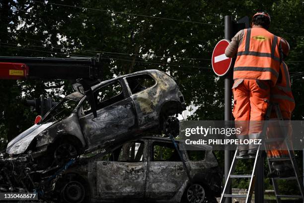 Workers repair traffic lights next to burned cars loaded onto a towing truck in the Aubiers neighborhood in Bordeaux, south-western France on late...