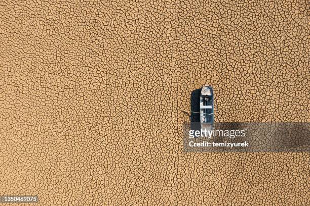 vista aérea de un barco de pesca en el lecho de un lago seco y seco por la sequía. - paisaje árido fotografías e imágenes de stock