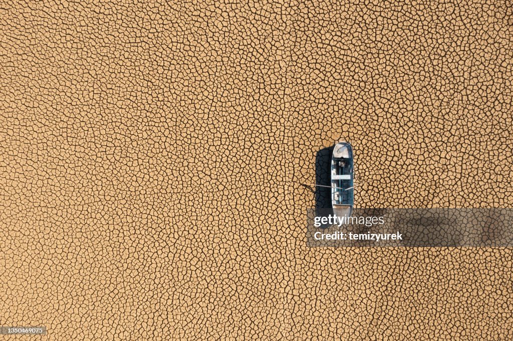 Vista aerea di una barca da pesca su un letto di lago asciutto dalla siccità.