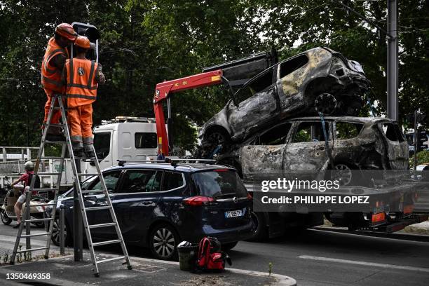 Workers repair traffic lights next to burned cars loaded onto a towing truck in the Aubiers neighborhood in Bordeaux, south-western France on late...