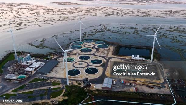 a energia sustentável é usada na conservação ambiental. uma estação de tratamento de águas residuais alimentada por turbinas eólicas e painéis solares perto de atlantic city, em nova jersey, eua. - águas residuais - fotografias e filmes do acervo