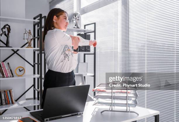 donna che si allunga mentre lavora da un ufficio a casa - ergonomia foto e immagini stock