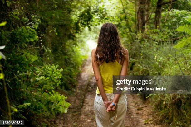 back view of young woman taking a spring walk - scheiding haardracht stockfoto's en -beelden