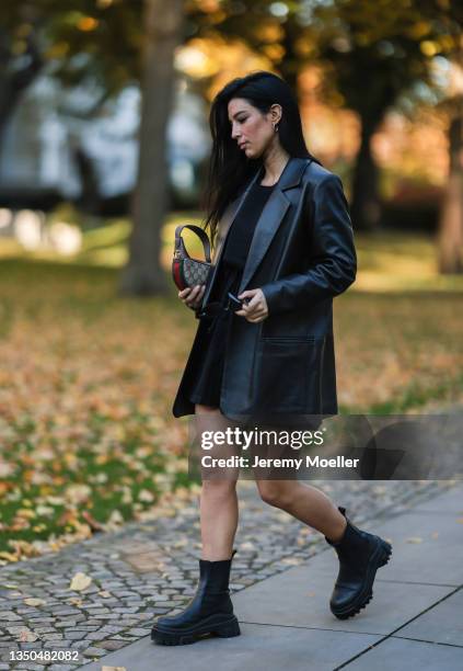 Semra Hunt wearing a mini Gucci monogramm bag, black leather jacket, Black Palm black jumpsuits, Prada black shades and black boots on October 28,...