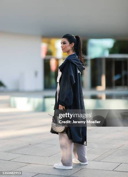 Semra Hunt wearing Nike Air Force white sneaker, beige jogging pants, a Jil Sander black parka, a white shirt, Celine black shades and Gucci mini...