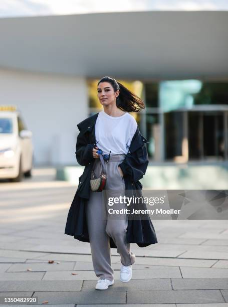 Semra Hunt wearing Nike Air Force white sneaker, beige jogging pants, a Jil Sander black parka, a white shirt, Celine black shades and Gucci mini...