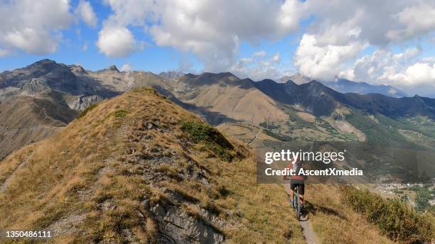 mountain biker follows trail on grassy mountain ridge - shorts down stock pictures, royalty-free photos & images