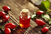 A bottle of rose hip seed oil with fresh rose hips