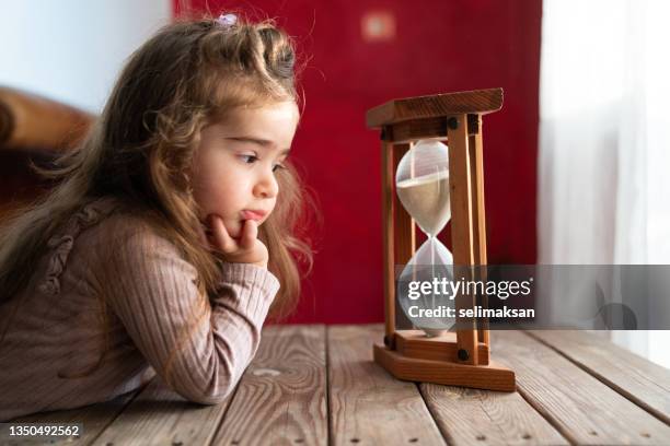 photo of little preschooler girl watching hourglass sand - timglas bildbanksfoton och bilder