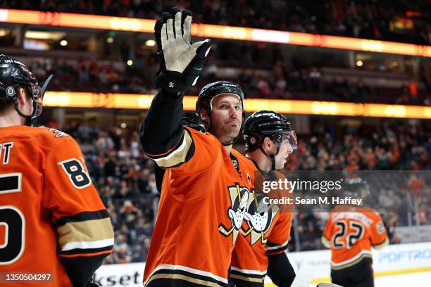 Simon Benoit and Derek Grant celebrate with Ryan Getzlaf as he waves to the crowd after an assist on a goal scored by Troy Terry of the Anaheim Ducks...