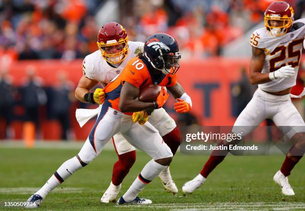 Jerry Jeudy of the Denver Broncos runs with the ball while being tackled by Cole Holcomb of the Washington Football Team in the fourth quarter at...