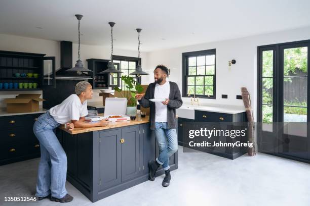 relaxed black couple enjoying pizza for lunch on moving day - kitchen island stock pictures, royalty-free photos & images